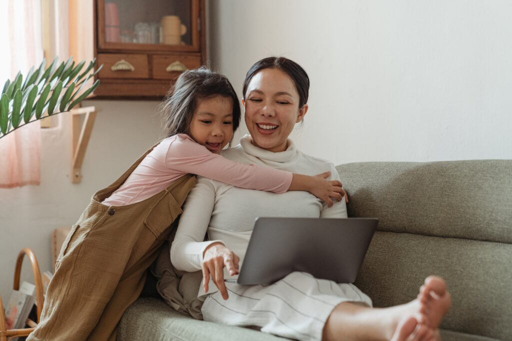 woman working from home whilst child hugs her
